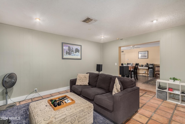 living room featuring light tile patterned flooring, a textured ceiling, and ceiling fan