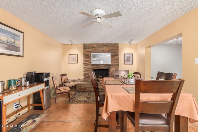 dining area with concrete flooring, a fireplace, ceiling fan, wood walls, and a textured ceiling