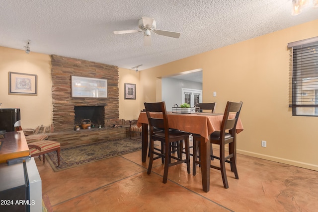 dining space with a fireplace, a textured ceiling, and ceiling fan