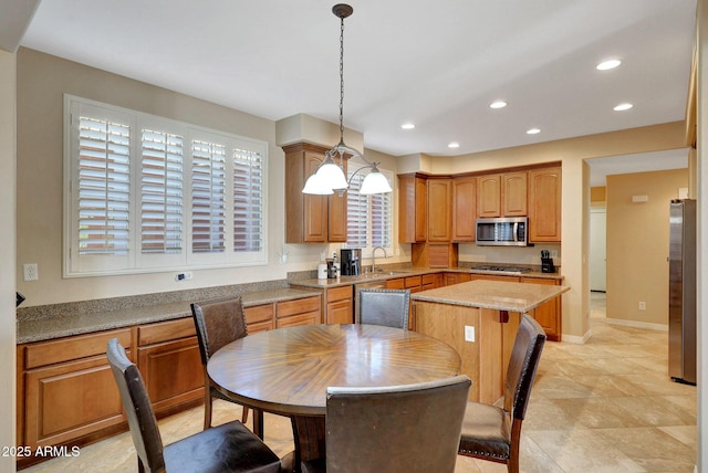 kitchen with a kitchen island, decorative light fixtures, stainless steel appliances, a sink, and recessed lighting