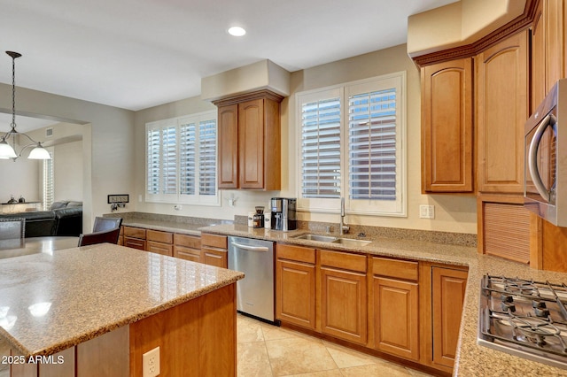 kitchen featuring stainless steel appliances, light stone counters, brown cabinetry, and pendant lighting