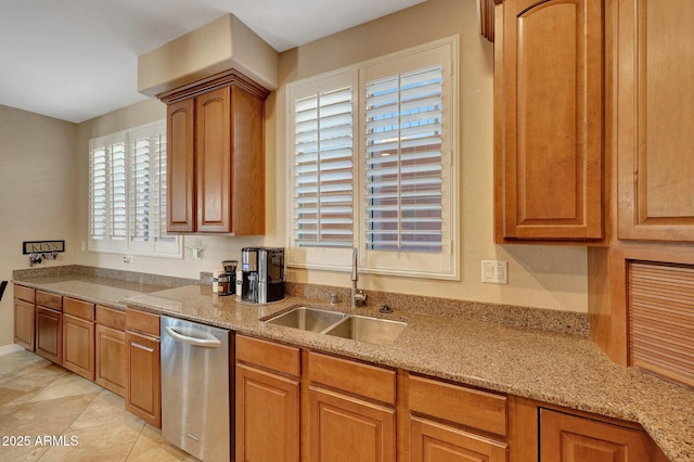 kitchen with light stone counters, brown cabinetry, and a sink