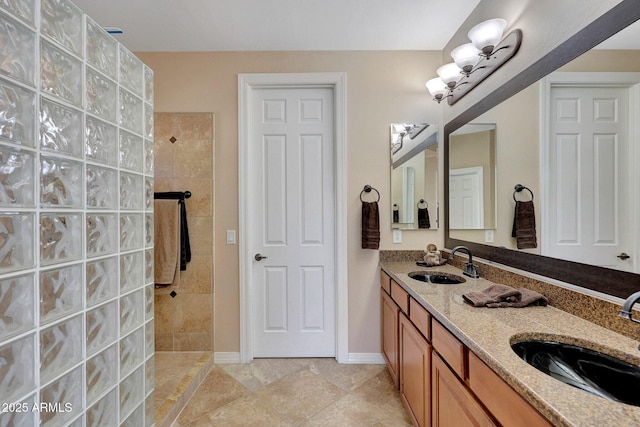 full bathroom featuring a walk in shower, double vanity, a sink, and baseboards