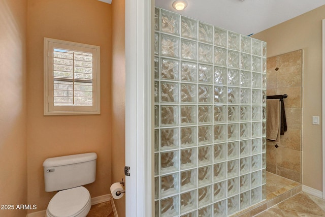 bathroom with baseboards, toilet, and walk in shower