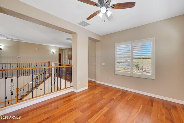 empty room with wood finished floors, visible vents, and baseboards