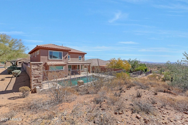 rear view of property with a tiled roof, fence, a fenced in pool, and stucco siding