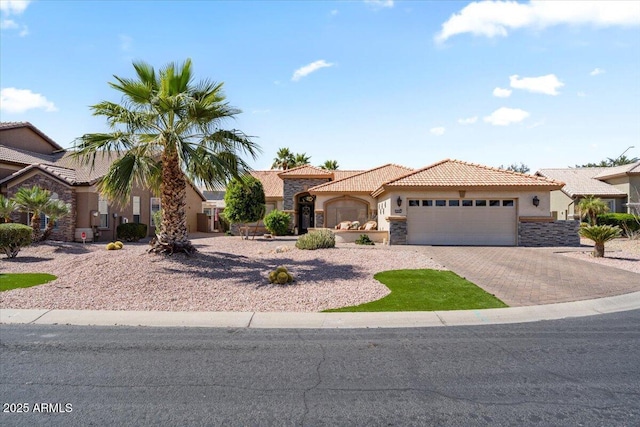 view of front of house featuring stucco siding, decorative driveway, stone siding, a garage, and a tiled roof