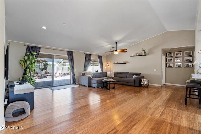 living room with baseboards, light wood finished floors, ceiling fan, and vaulted ceiling