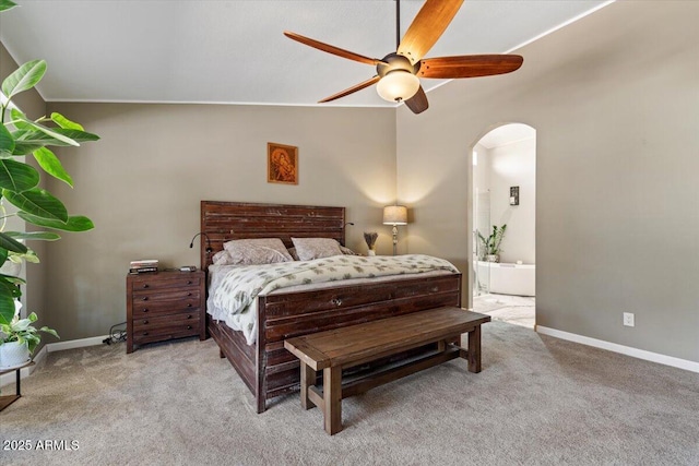 carpeted bedroom with ceiling fan, baseboards, arched walkways, and connected bathroom