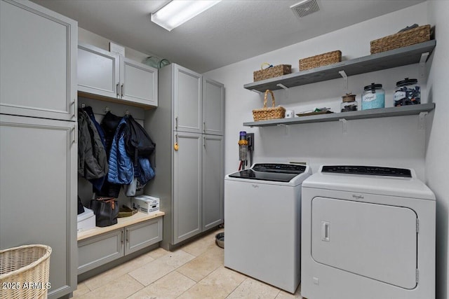 washroom featuring visible vents, cabinet space, and washer and dryer