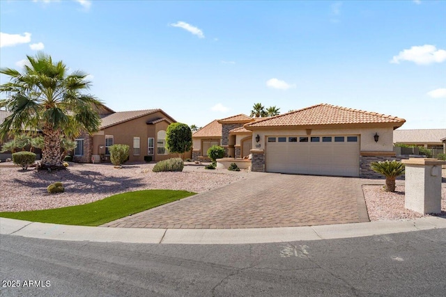 mediterranean / spanish-style home featuring stucco siding, a garage, stone siding, a tiled roof, and decorative driveway