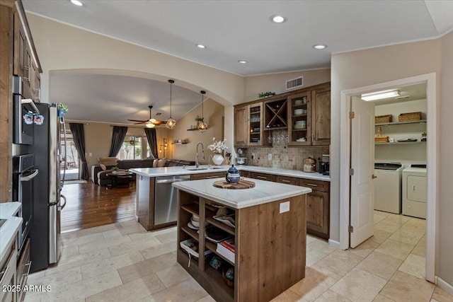 kitchen with visible vents, washing machine and clothes dryer, a peninsula, a sink, and dishwasher