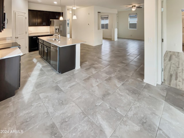 kitchen with a kitchen island with sink, sink, hanging light fixtures, ceiling fan, and stainless steel appliances