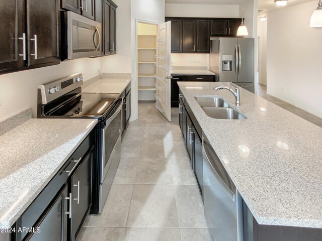 kitchen with light stone countertops, appliances with stainless steel finishes, dark brown cabinets, and hanging light fixtures