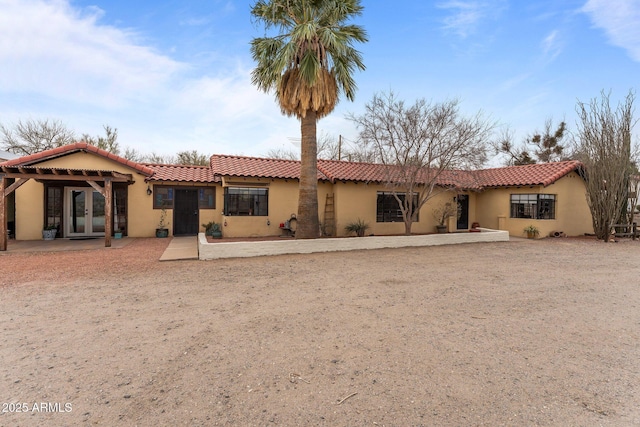 rear view of property featuring a tiled roof, french doors, and stucco siding