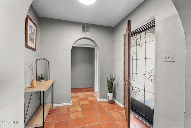 foyer with visible vents, arched walkways, baseboards, and tile patterned flooring