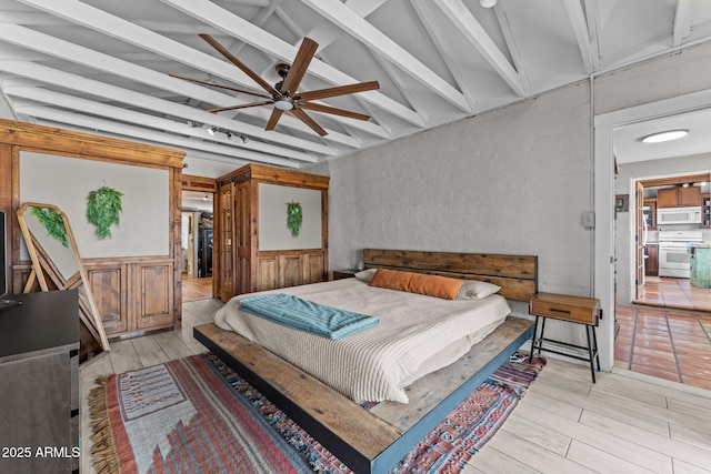 bedroom with light wood-style flooring and vaulted ceiling with beams