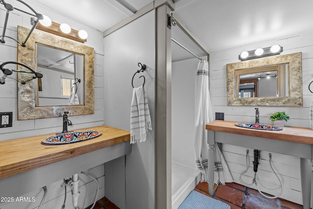 full bathroom with curtained shower, wood walls, and a sink