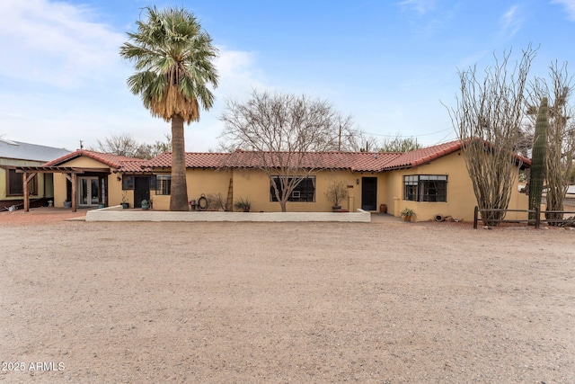 view of front of house featuring a tiled roof, fence, and stucco siding