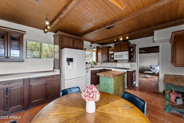 kitchen featuring visible vents, dark tile patterned flooring, a center island, white appliances, and wood ceiling