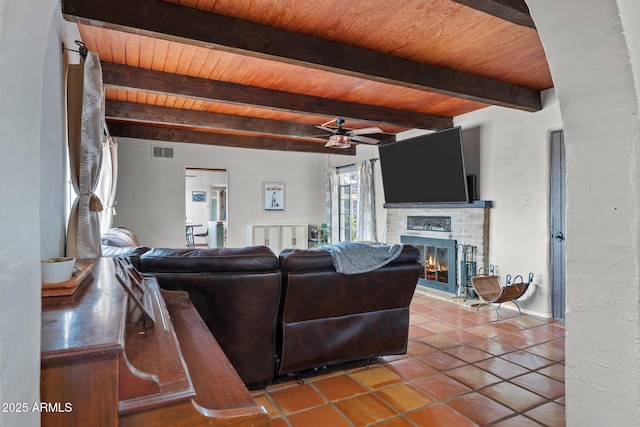 living area featuring visible vents, tile patterned flooring, a brick fireplace, wood ceiling, and beamed ceiling