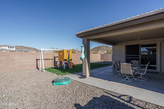 view of patio / terrace with a playground and a mountain view