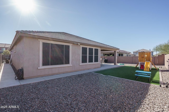 rear view of house with a playground and a patio area