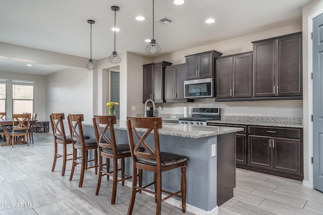 kitchen with decorative light fixtures, a kitchen breakfast bar, range, light stone counters, and dark brown cabinetry