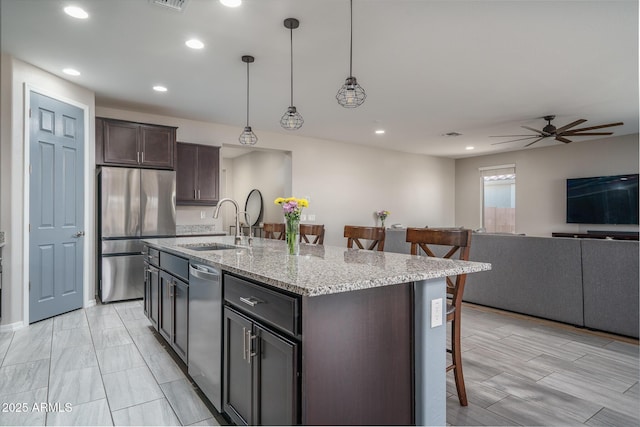 kitchen featuring decorative light fixtures, stainless steel appliances, sink, a center island with sink, and a breakfast bar area