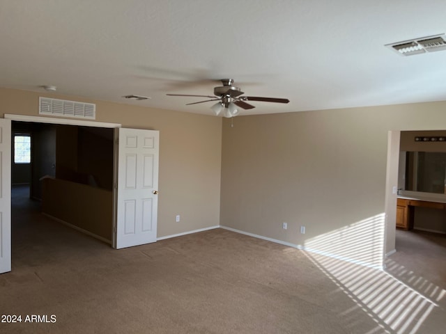 carpeted spare room featuring ceiling fan