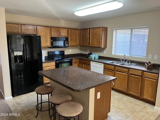 kitchen featuring sink, a center island, a breakfast bar area, and black appliances