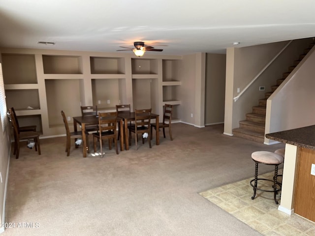 carpeted dining room with built in features and ceiling fan