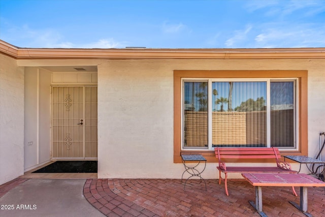 entrance to property with stucco siding and a patio