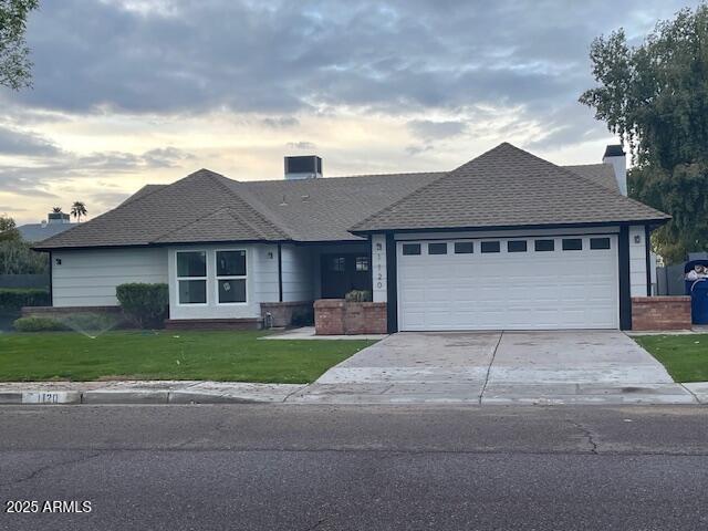 single story home featuring a garage, brick siding, driveway, a front lawn, and a chimney