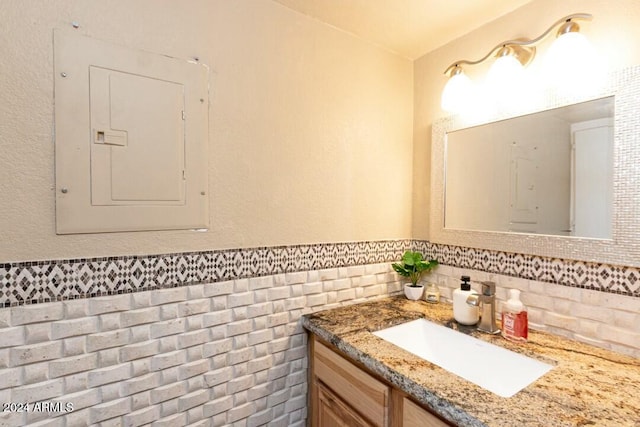 bathroom featuring electric panel, vanity, and tile walls