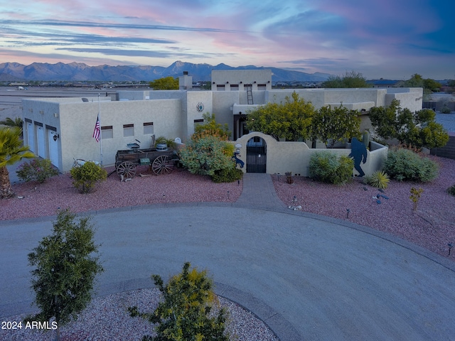 pueblo-style house featuring a garage and a mountain view