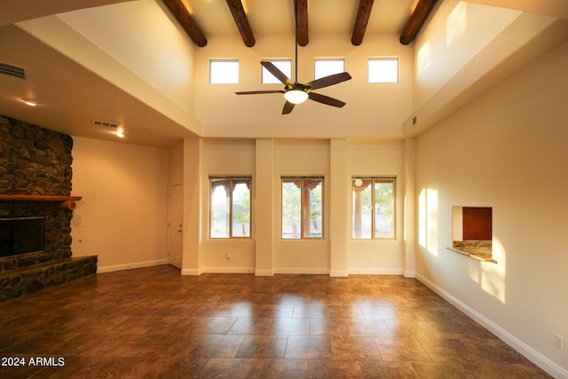 unfurnished living room featuring a fireplace, beamed ceiling, and a healthy amount of sunlight