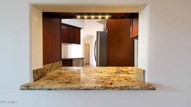 kitchen featuring light tile patterned floors, light stone countertops, wall chimney exhaust hood, appliances with stainless steel finishes, and sink