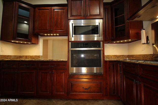 kitchen featuring stone counters, stainless steel appliances, and extractor fan