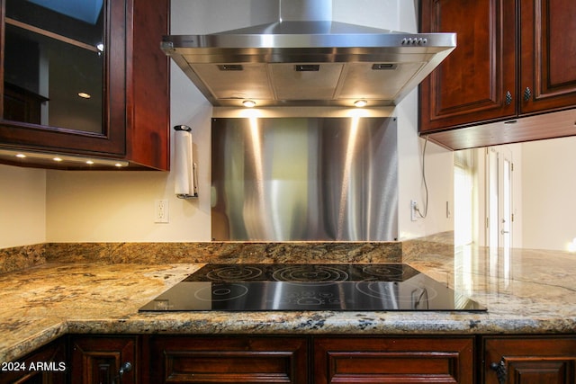 kitchen featuring light stone countertops, black electric cooktop, and range hood