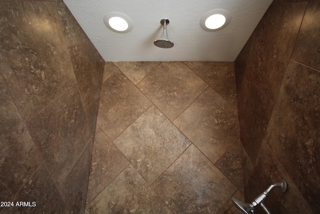 room details featuring a textured ceiling and a tile shower