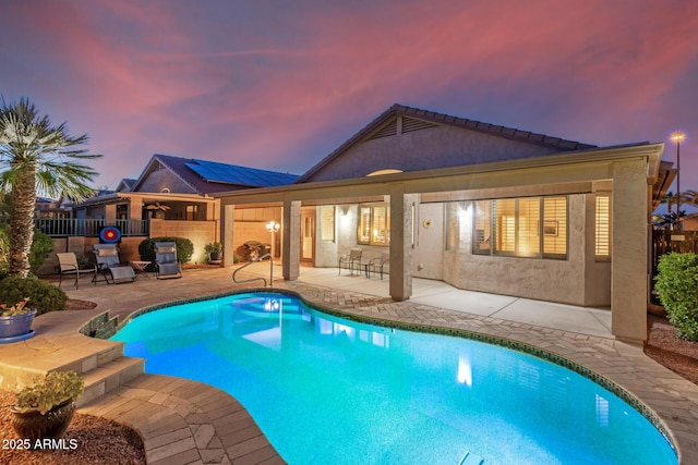 pool at dusk with a fenced in pool, a patio area, and fence