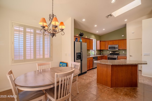 kitchen with appliances with stainless steel finishes, a kitchen island, visible vents, and brown cabinets