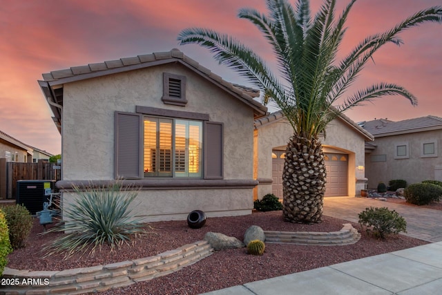 view of front of home with cooling unit, decorative driveway, and stucco siding