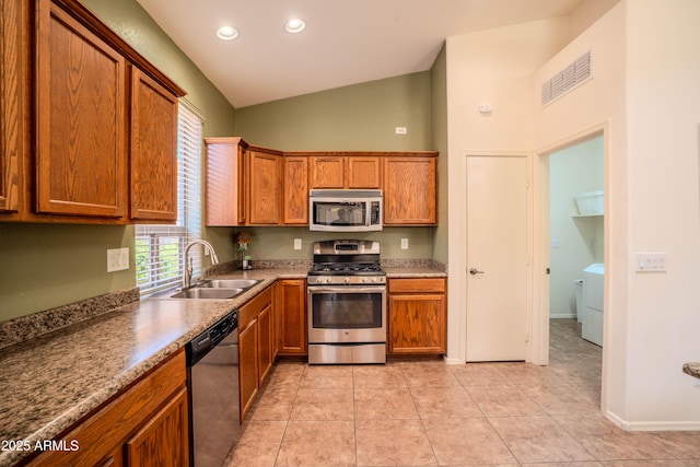 kitchen with stainless steel appliances, visible vents, brown cabinetry, vaulted ceiling, and a sink