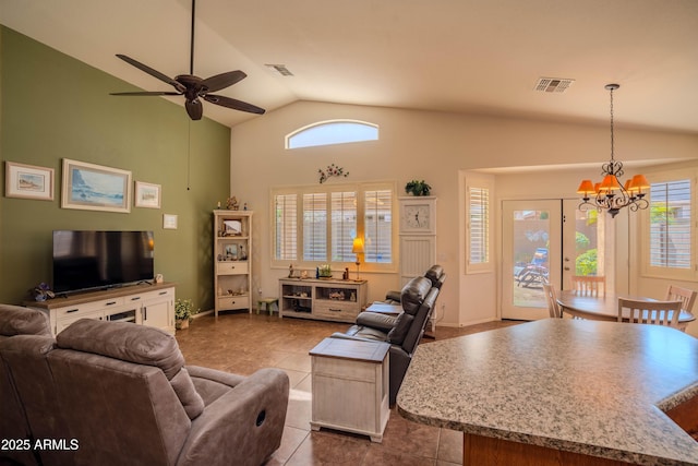 living area featuring vaulted ceiling, dark tile patterned flooring, ceiling fan with notable chandelier, and visible vents