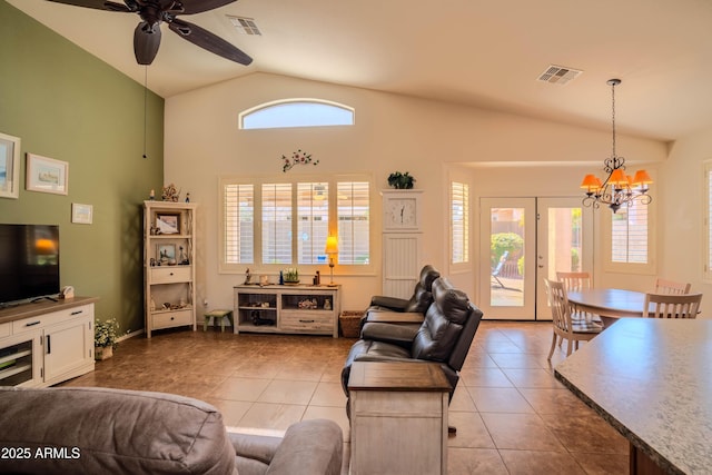 tiled living room featuring french doors, visible vents, vaulted ceiling, and ceiling fan with notable chandelier