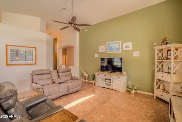 living area featuring arched walkways, visible vents, a ceiling fan, vaulted ceiling, and baseboards