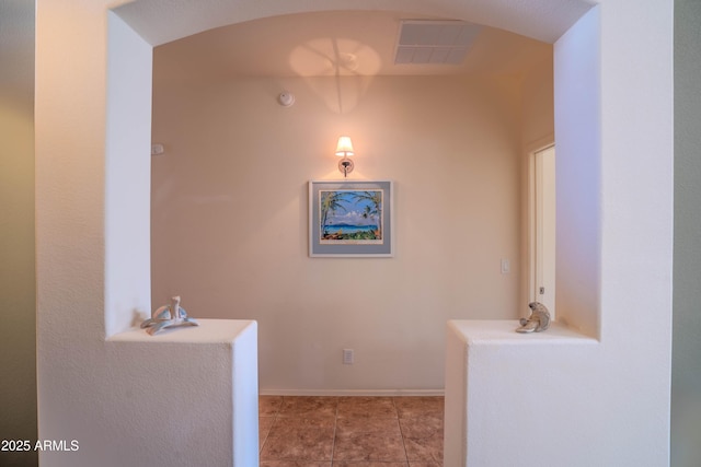 hallway featuring baseboards, visible vents, and arched walkways