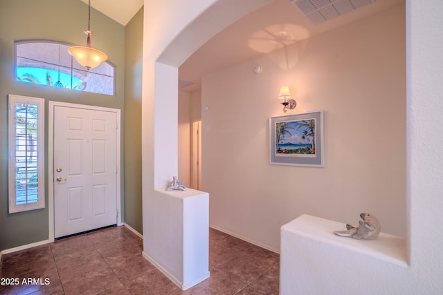 tiled entrance foyer featuring arched walkways, visible vents, and baseboards